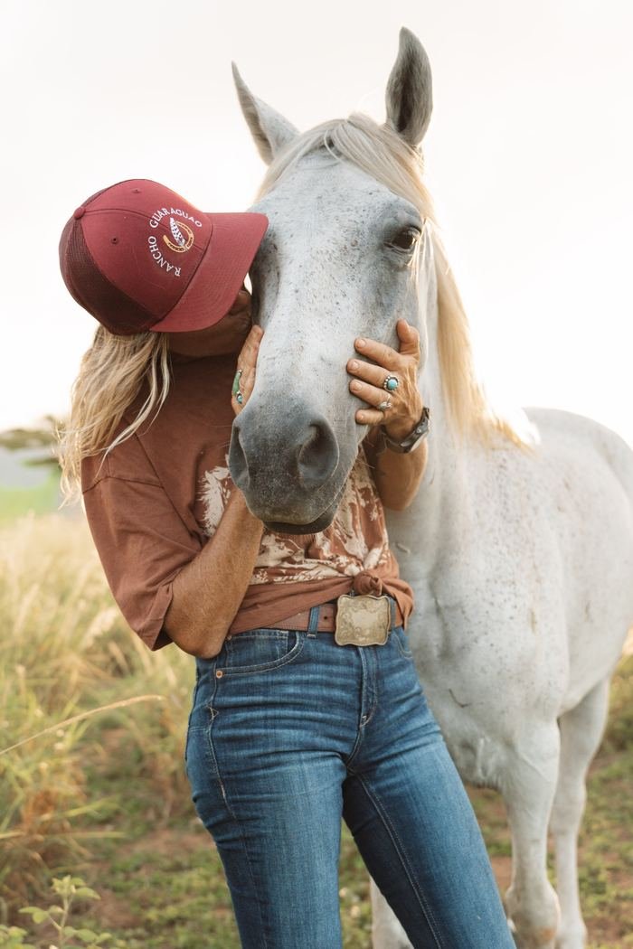 A gentle moment between a rider and a white horse at the ranch